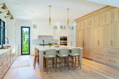 Inspiration for a large transitional light wood floor eat-in kitchen remodel in New York with a farmhouse sink, light wood cabinets, marble countertops, multicolored backsplash, marble backsplash, stainless steel appliances, an island and white countertops
