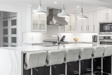 Large trendy u-shaped medium tone wood floor and brown floor open concept kitchen photo in Toronto with an undermount sink, flat-panel cabinets, white cabinets, quartz countertops, white backsplash, porcelain backsplash, stainless steel appliances, an island and white countertops