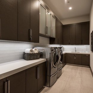Photo of a medium sized contemporary l-shaped separated utility room in Las Vegas with a submerged sink, flat-panel cabinets, brown cabinets, engineered stone countertops, white walls, porcelain flooring, a side by side washer and dryer, beige floors and white worktops.