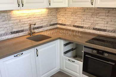 Immagine di una cucina a L di medie dimensioni con lavello integrato, top in superficie solida e top marrone