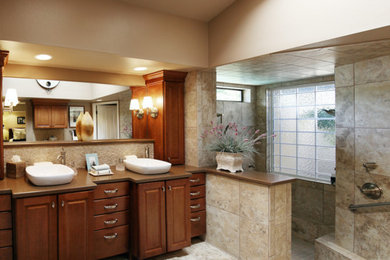 Bathroom - mid-sized traditional master beige tile and ceramic tile travertine floor and beige floor bathroom idea in Other with medium tone wood cabinets, beige walls, raised-panel cabinets, a two-piece toilet, a hinged shower door, a vessel sink, solid surface countertops and brown countertops