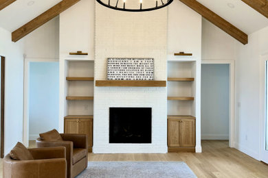 Inspiration for a mid-sized modern light wood floor, brown floor and vaulted ceiling living room remodel in Atlanta with white walls and a brick fireplace