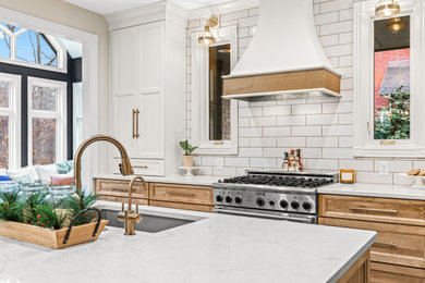 Mid-sized transitional l-shaped laminate floor and brown floor eat-in kitchen photo in Detroit with an undermount sink, recessed-panel cabinets, white cabinets, quartz countertops, white backsplash, porcelain backsplash, stainless steel appliances, an island and white countertops