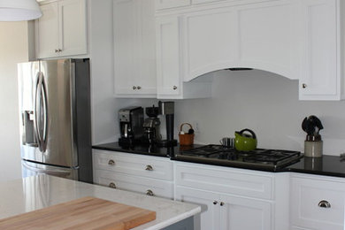 Example of a large classic medium tone wood floor kitchen design in Chicago with shaker cabinets, white cabinets, marble countertops, stainless steel appliances and an island