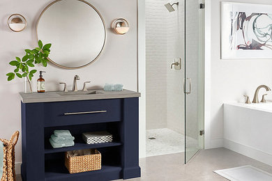 Design ideas for a mid-sized transitional master bathroom in Salt Lake City with furniture-like cabinets, blue cabinets, an alcove tub, an alcove shower, grey walls, laminate floors, an integrated sink, concrete benchtops, grey floor and a hinged shower door.