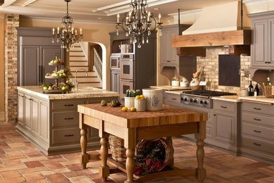 Inspiration for a large rustic u-shaped travertine floor enclosed kitchen remodel in Other with a farmhouse sink, raised-panel cabinets, gray cabinets, granite countertops, beige backsplash, brick backsplash, paneled appliances and two islands