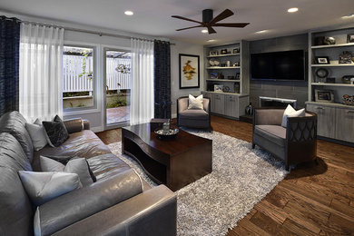 Inspiration for a mid-sized transitional enclosed family room in Orange County with grey walls, dark hardwood floors, a standard fireplace, a tile fireplace surround, a wall-mounted tv and brown floor.