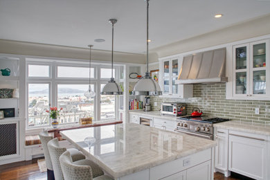 Mid-sized elegant l-shaped medium tone wood floor, brown floor and tray ceiling eat-in kitchen photo in San Francisco with a single-bowl sink, shaker cabinets, white cabinets, marble countertops, green backsplash, subway tile backsplash, stainless steel appliances, an island and white countertops