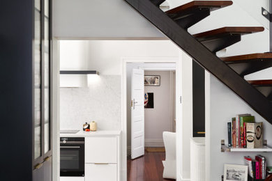 パースにある高級な広いモダンスタイルのおしゃれなキッチン (アンダーカウンターシンク、フラットパネル扉のキャビネット、白いキャビネット、クオーツストーンカウンター、白いキッチンパネル、クオーツストーンのキッチンパネル、黒い調理設備、濃色無垢フローリング、茶色い床、白いキッチンカウンター) の写真