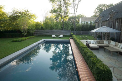 This is an example of a mid-sized contemporary backyard rectangular lap pool in New York with a water feature and concrete slab.