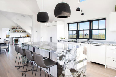Beach style light wood floor and beige floor kitchen photo in Other with an undermount sink, flat-panel cabinets, white cabinets, paneled appliances, an island and multicolored countertops