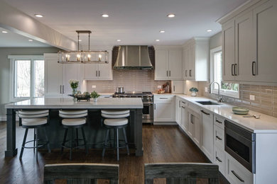 Example of a large transitional l-shaped medium tone wood floor and brown floor kitchen pantry design in Chicago with an undermount sink, recessed-panel cabinets, gray cabinets, quartz countertops, gray backsplash, ceramic backsplash, paneled appliances, an island and gray countertops