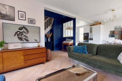 Cette photo montre une salle de séjour rétro de taille moyenne et ouverte avec un mur beige, parquet clair et un téléviseur fixé au mur.