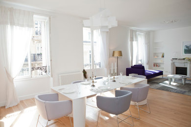 Cette photo montre une grande salle à manger ouverte sur le salon tendance avec un mur blanc, parquet clair, une cheminée standard, un manteau de cheminée en pierre et un sol marron.