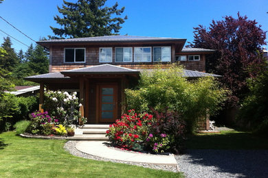 Example of a mid-sized beach style brown two-story wood and shingle house exterior design in Vancouver with a hip roof, a metal roof and a gray roof