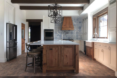 Example of a large cottage u-shaped brick floor, multicolored floor and exposed beam eat-in kitchen design in Austin with a farmhouse sink, shaker cabinets, medium tone wood cabinets, granite countertops, blue backsplash, porcelain backsplash, stainless steel appliances, an island and white countertops