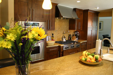Enclosed kitchen - large contemporary u-shaped travertine floor enclosed kitchen idea in Los Angeles with an undermount sink, shaker cabinets, dark wood cabinets, granite countertops, beige backsplash, stone slab backsplash, stainless steel appliances and an island