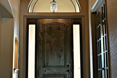 Large mountain style dark wood floor and brown floor entryway photo in Other with beige walls and a dark wood front door