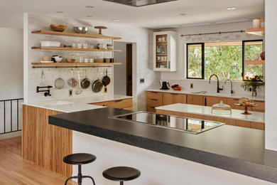 Inspiration for a mid-sized 1950s u-shaped medium tone wood floor kitchen remodel in Portland with an undermount sink, flat-panel cabinets, light wood cabinets, quartz countertops, white backsplash, ceramic backsplash, stainless steel appliances, an island and white countertops