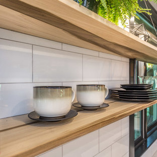 This is an example of a large industrial l-shaped kitchen pantry in Manchester with an undermount sink, flat-panel cabinets, black cabinets, quartz benchtops, white splashback, porcelain splashback, stainless steel appliances, cement tiles, with island, grey floor and white benchtop.