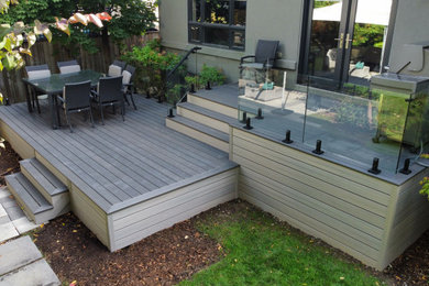 Diseño de terraza minimalista de tamaño medio en patio trasero con barandilla de vidrio