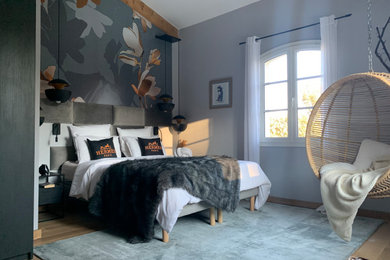 Modelo de dormitorio principal y gris y negro contemporáneo grande sin chimenea con paredes grises, suelo de madera clara, suelo beige, vigas vistas y papel pintado