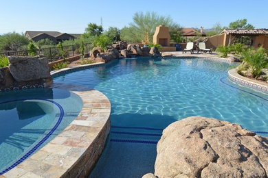 Inspiration for a large traditional backyard infinity pool in Phoenix with a water feature.