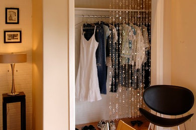 Example of a small trendy gender-neutral light wood floor walk-in closet design in Austin with white cabinets