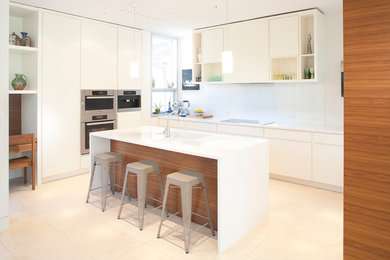 Large minimalist u-shaped ceramic tile open concept kitchen photo in Toronto with a drop-in sink, flat-panel cabinets, white cabinets, solid surface countertops, white backsplash, glass sheet backsplash, stainless steel appliances and an island
