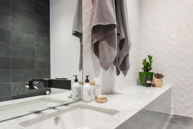 This is an example of a large contemporary 3/4 bathroom in Melbourne with an open shower, a wall-mount toilet, white tile, ceramic tile, an integrated sink, marble benchtops, an open shower, multi-coloured benchtops and a built-in vanity.