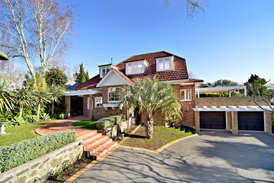 Traditional beige two-story brick exterior home idea in Auckland