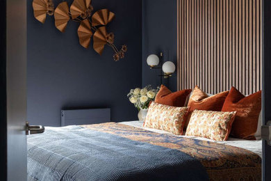 Small contemporary master bedroom in London with blue walls and panelled walls.