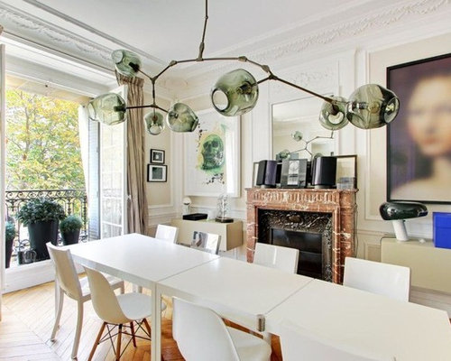 Inspiration pour une salle à manger design avec un mur blanc, un sol en bois brun et une cheminée standard.