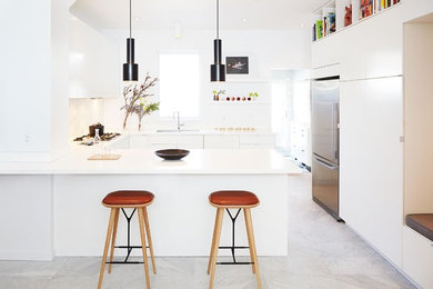 Mid-sized modern u-shaped kitchen in Toronto with flat-panel cabinets, white cabinets, solid surface benchtops, stainless steel appliances, marble floors, a double-bowl sink, white splashback, marble splashback, a peninsula and grey floor.