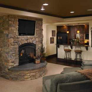 Inspiration for a large rustic fully buried basement in Denver with beige walls, carpet, a two-sided fireplace, a stone fireplace surround and beige floors.