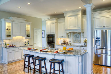 Inspiration for a mid-sized timeless l-shaped light wood floor enclosed kitchen remodel in Other with white cabinets, granite countertops, white backsplash, mosaic tile backsplash, an island, an undermount sink, raised-panel cabinets and stainless steel appliances