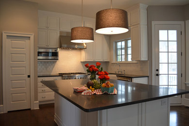 Open concept kitchen - huge traditional u-shaped dark wood floor open concept kitchen idea in Wilmington with a farmhouse sink, recessed-panel cabinets, white cabinets, granite countertops, white backsplash, ceramic backsplash, stainless steel appliances and an island