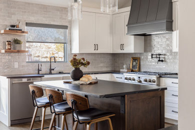Large transitional u-shaped laminate floor and brown floor eat-in kitchen photo in Salt Lake City with a farmhouse sink, recessed-panel cabinets, white cabinets, granite countertops, gray backsplash, subway tile backsplash, stainless steel appliances, an island and black countertops