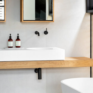 Foto di una piccola stanza da bagno con doccia minimal con ante di vetro, vasca freestanding, doccia aperta, pareti bianche, lavabo sospeso, top in legno, doccia aperta e top marrone