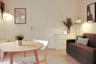 Small scandinavian open concept living room in Paris with white walls, laminate floors and a freestanding tv.