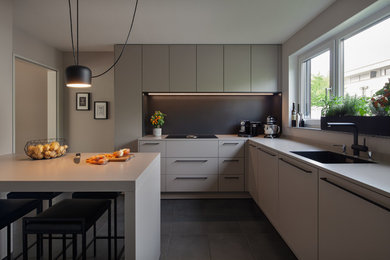 Offene, Große Moderne Küche in L-Form mit integriertem Waschbecken, flächenbündigen Schrankfronten, grauen Schränken, Mineralwerkstoff-Arbeitsplatte, Küchenrückwand in Schwarz, Rückwand aus Holz, Küchengeräten aus Edelstahl, Zementfliesen für Boden, Kücheninsel, schwarzem Boden und grauer Arbeitsplatte in Köln