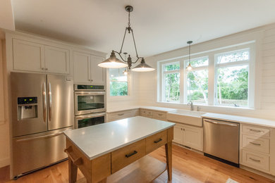 Inspiration for a large u-shaped light wood floor eat-in kitchen remodel in Providence with a farmhouse sink, recessed-panel cabinets, white cabinets, quartzite countertops, white backsplash, terra-cotta backsplash, stainless steel appliances and an island