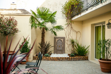 Photo of a mid-sized mediterranean front yard patio in Paris with a water feature, natural stone pavers and no cover.