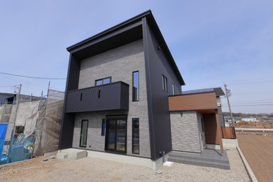Aménagement d'une façade de maison grise moderne en planches et couvre-joints à un étage avec un toit en appentis, un toit en métal et un toit noir.