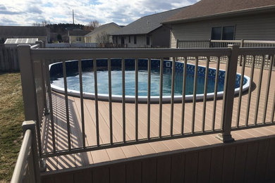 Example of a mid-sized classic backyard round pool design in Other with decking