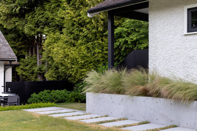 Ispirazione per un grande giardino formale chic esposto in pieno sole dietro casa in estate con un muro di contenimento, pavimentazioni in cemento e recinzione in metallo
