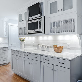 Mid-sized traditional kitchen pantry inspiration - Inspiration for a mid-sized timeless u-shaped medium tone wood floor kitchen pantry remodel in Providence with a farmhouse sink, shaker cabinets, gray cabinets, granite countertops, white backsplash, subway tile backsplash and stainless steel appliances