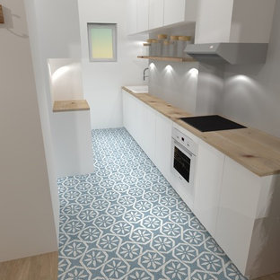 Пример оригинального дизайна интерьера: маленькая линейная кухня-гостиная в стиле фьюжн с врезной раковиной, белыми фасадами, столешницей из дерева, серым фартуком, техникой из нержавеющей стали, полом из цементной плитки и синим полом без острова