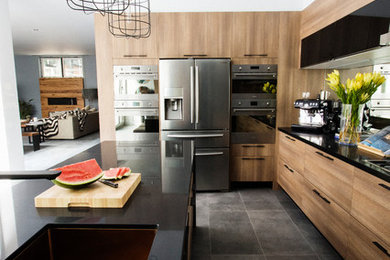 Photo of a contemporary u-shaped kitchen in Melbourne with medium wood cabinets, granite benchtops, mirror splashback, stainless steel appliances, ceramic floors and with island.