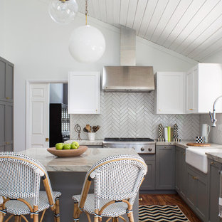 Réalisation d'une arrière-cuisine tradition en U de taille moyenne avec un évier de ferme, un placard à porte shaker, des portes de placard grises, un plan de travail en quartz modifié, une crédence blanche, une crédence en carreau de porcelaine, un électroménager en acier inoxydable, un sol en bois brun et un îlot central.